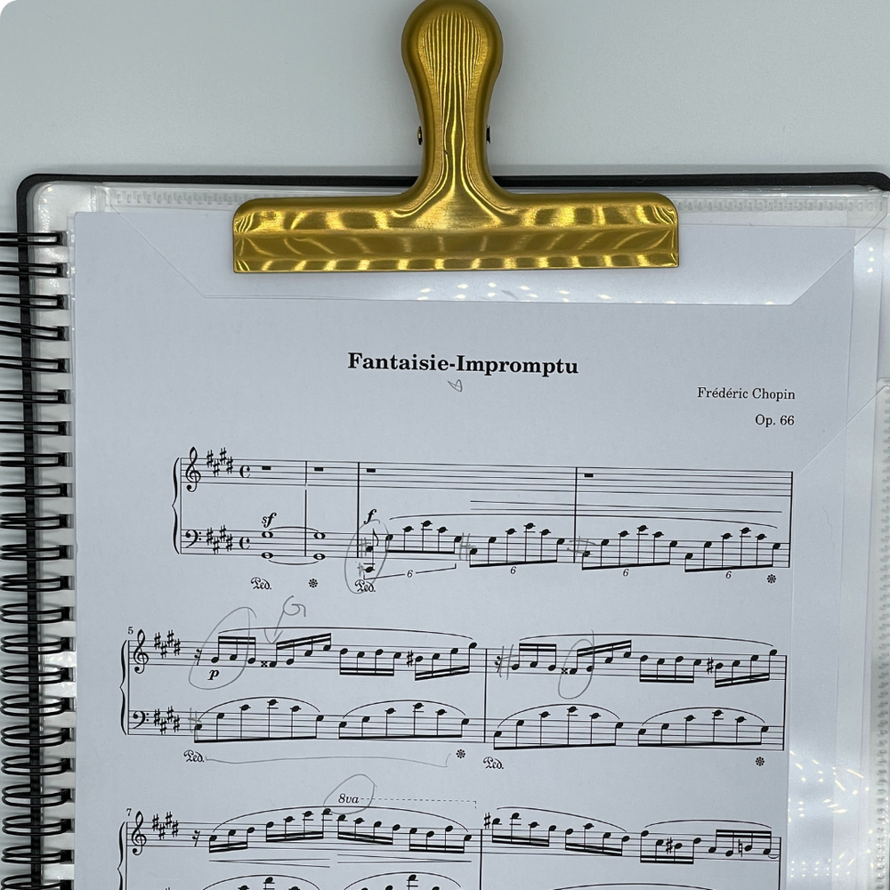 Gold stainless steel sheet music clip securely holding Fantaisie-Impromptu by Chopin on Piano Glory A4 Music Folder — elegant, durable clip designed to keep sheet music in place during piano practice or performance.