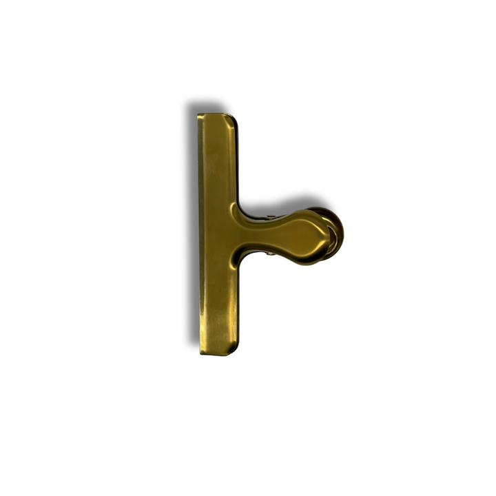 Side view of gold stainless steel sheet music clip — sturdy, wide-grip design ideal for holding sheet music in place on music stands or pianos.